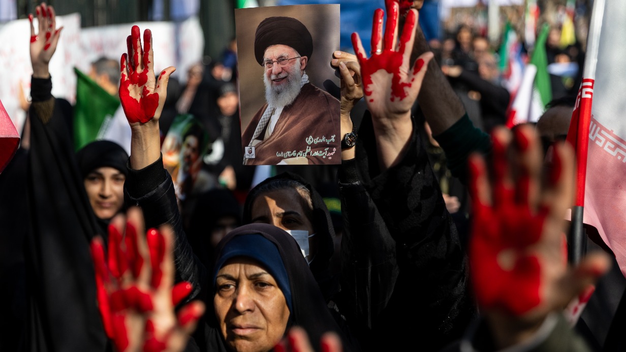Митинг в центре Тегерана. Женщины, выкрасив ладони красной краской, несут портрет аятоллы Али Хаменеи, убитого в день нападения Израиля и Америки на Иран