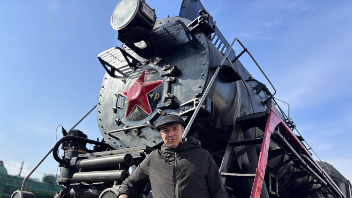 Машинист Сергей Бендюков рядом с именным паровозом ЛВ-0182, на будке которого можно прочесть его фамилию