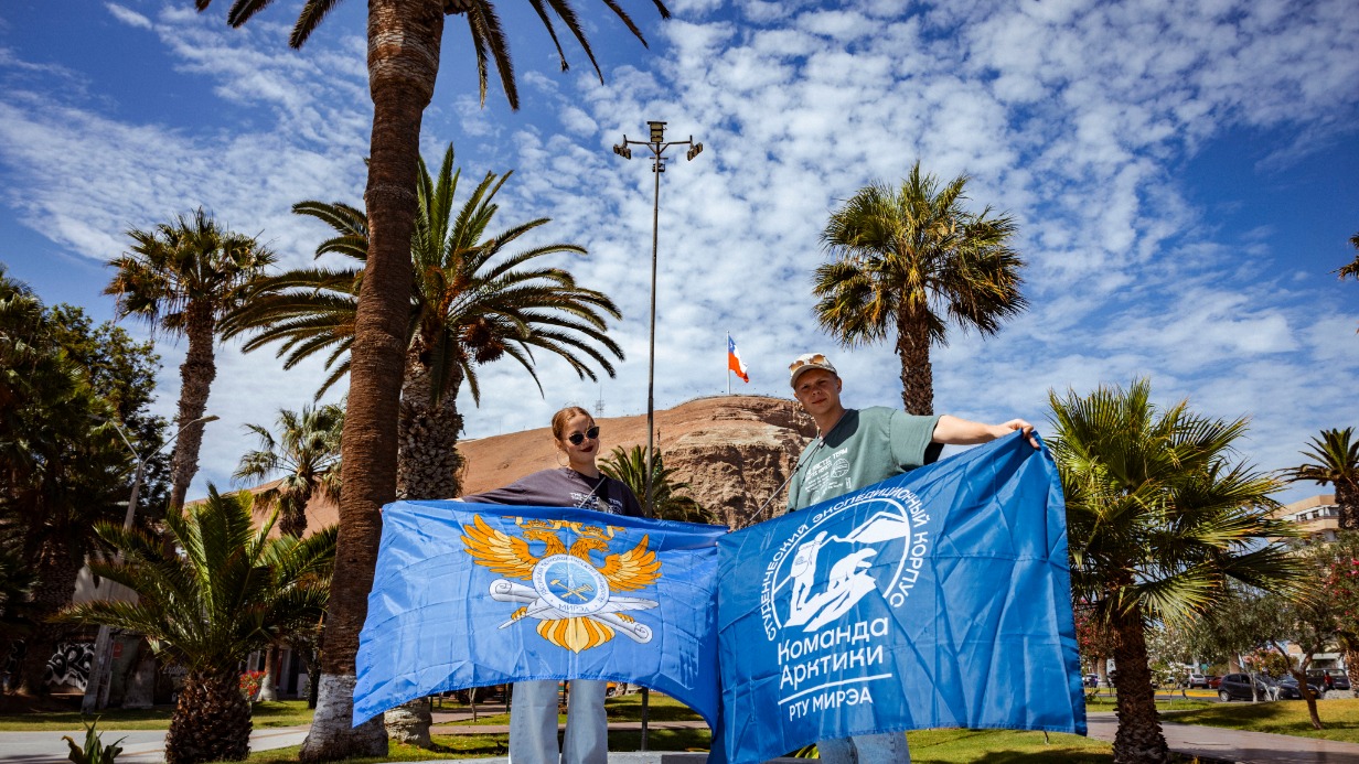 Участники кругосветного путешествия от РТУ МИРЭА Александра Тимофеева и Александр Калинин держат флаги университета и «Команды Арктики» в городе Арика в Чили