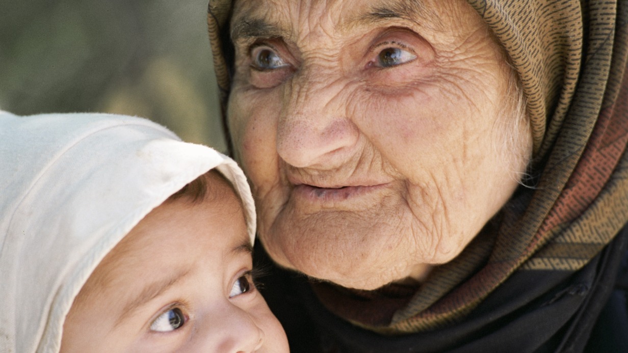 104-летняя жительница селения Верхний Джалган Гульзар Амурханова держит на руках своего правнука. Пока ее дочери и внучки работают, прабабушка нянчит малышей