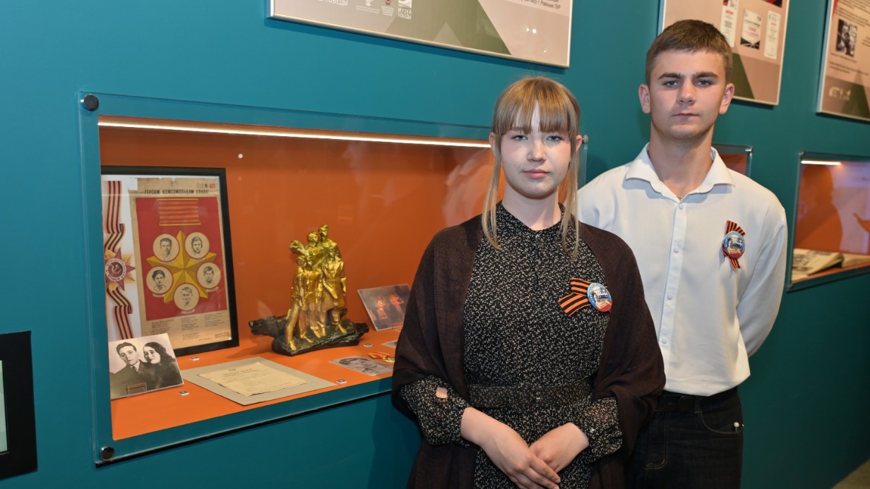 Ученики Антрацитовской основной школы № 1 — лицея имени Героя СССР Олега Кошевого в ЛНР Алена Худолий и Константин Линько на фоне копии памятника молодогвардейцам в городе Ровеньки, ЛНР