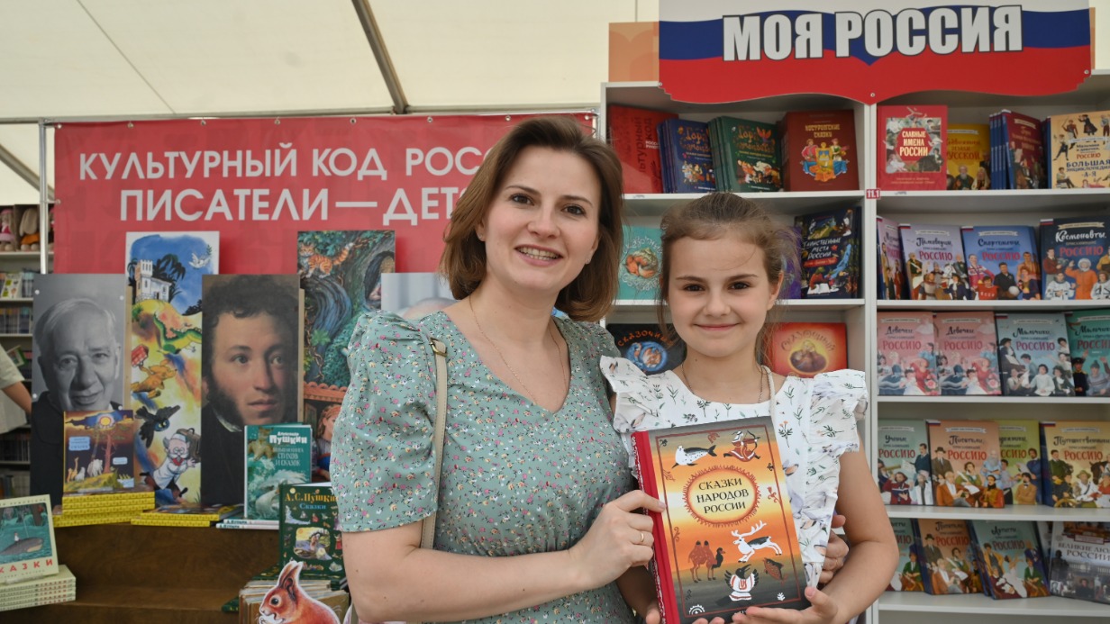 Посетители XII Книжного фестиваля «Красная площадь» Ксения Третьяк и ее дочь Василиса рассматривают представленные издания