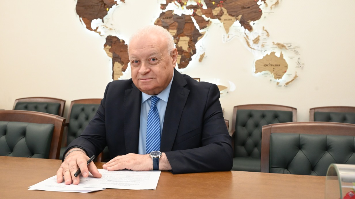 Исполнительный директор Фонда поддержки и защиты прав соотечественников, проживающих за рубежом, потомственный дипломат Александр Удальцов рассказывает об открытии правозащитных центров по всему миру — за его спиной расположена карта с флажками, отмечающими эти организации