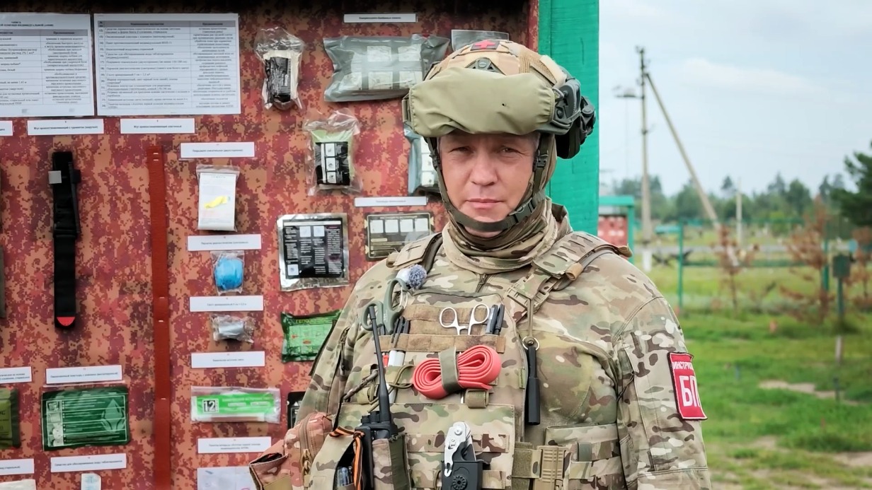15 августа. Инструктор мотострелкового полка резерва Московского военного округа с позывным «Шаман» рядом со стендом, на котором показано наполнение тактической полевой аптечки