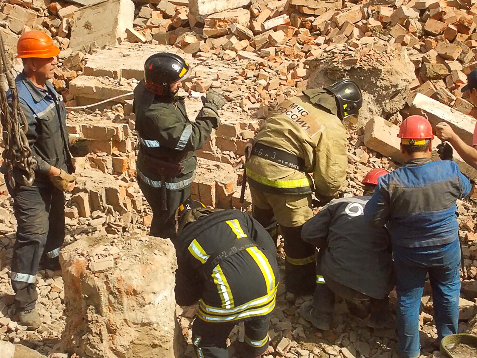 Спасательные работы при землетрясении. Люди под завалами обрушившихся зданий. Человек под обломками здания. Спасатели на обрушении здания.